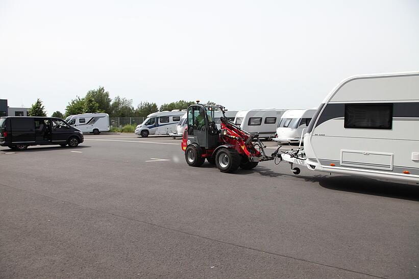 Weidemann Hoftrac 1280 rangiert mit einem Wohnwagen