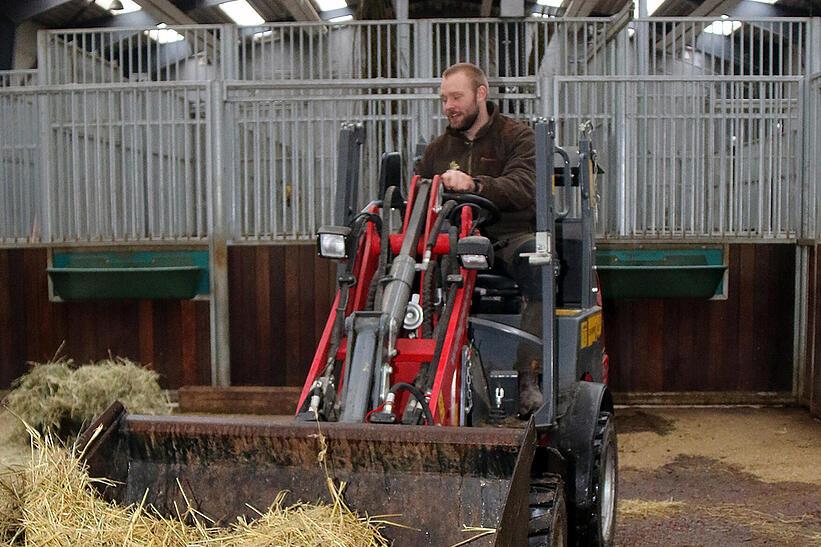 Ein Tierpfleger sitzt auf einem Weidemann und transportiert Stroh in ein Tiergehege