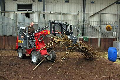 An animal keeper sitting on an eHoftrac 1160 transporting branches into an animal enclosure