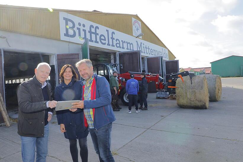 Drei Menschen stehen vor dem Stall der Büffelfarm