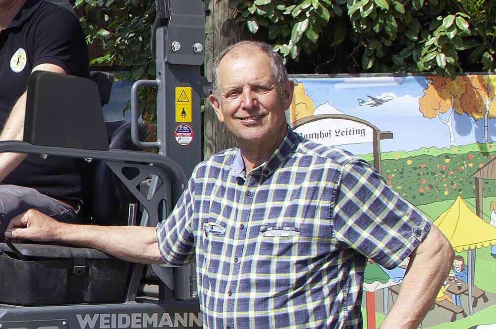 Mehrere Menschen stehen um einen Weidemann Hoftrac 1160e mit Fahrerschutzdach