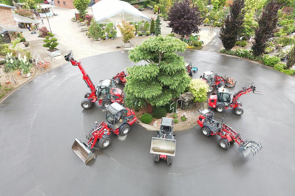 Eight Weidemann machines standing in a circle around a tree